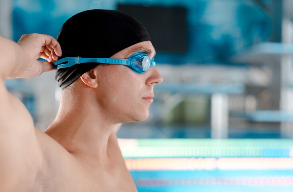 A man putting on goggles before getting in a pool to protect his eyes while wearing contact lenses.