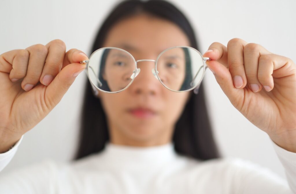 A woman is holding her glasses as she sees a decline in her astigmatism condition.